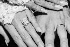 Hailey Bieber's hand with an Oval Solitaire engagement ring and bridal stack next to Justin Bieber's hand with a wedding band. | Hitched Fine Jewelry
