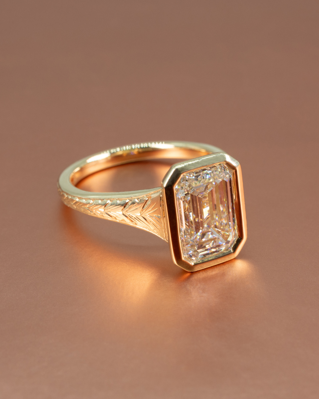 Bezel set emerald engagement ring with hand engraving