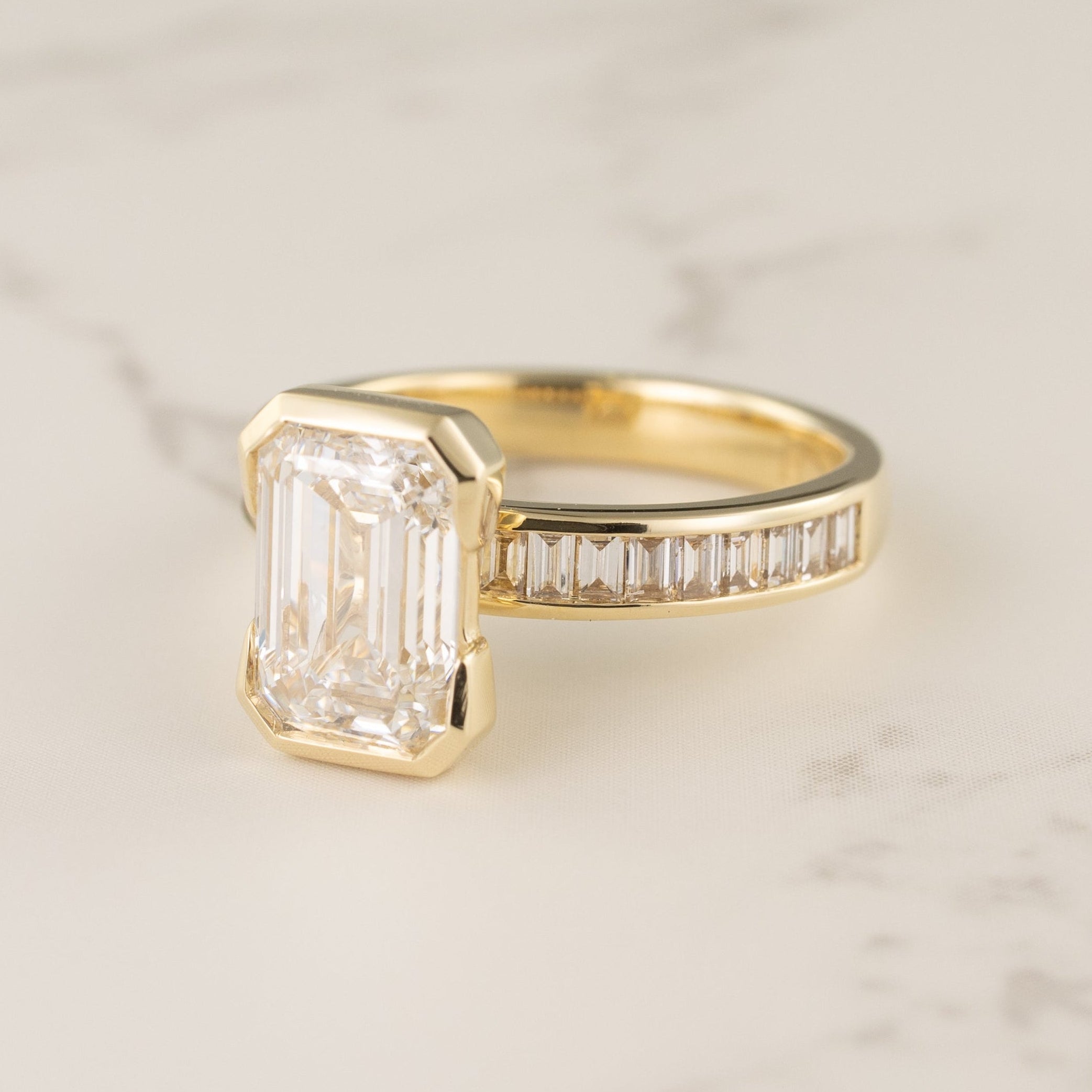 Half-bezel engagement ring setting with channel baguette side stones
