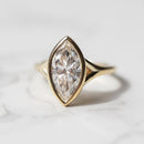 The front view of a split shank bezel engagement ring. The ring has a large marquise in the center and is set in yellow gold.