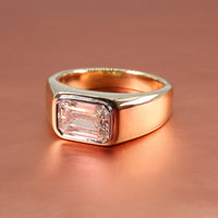 Chunky east-west tapered cigar band engagement ring setting on a rose gold background