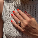 a model showing a large chunky gold engagement ring with a cushion cut center diamond