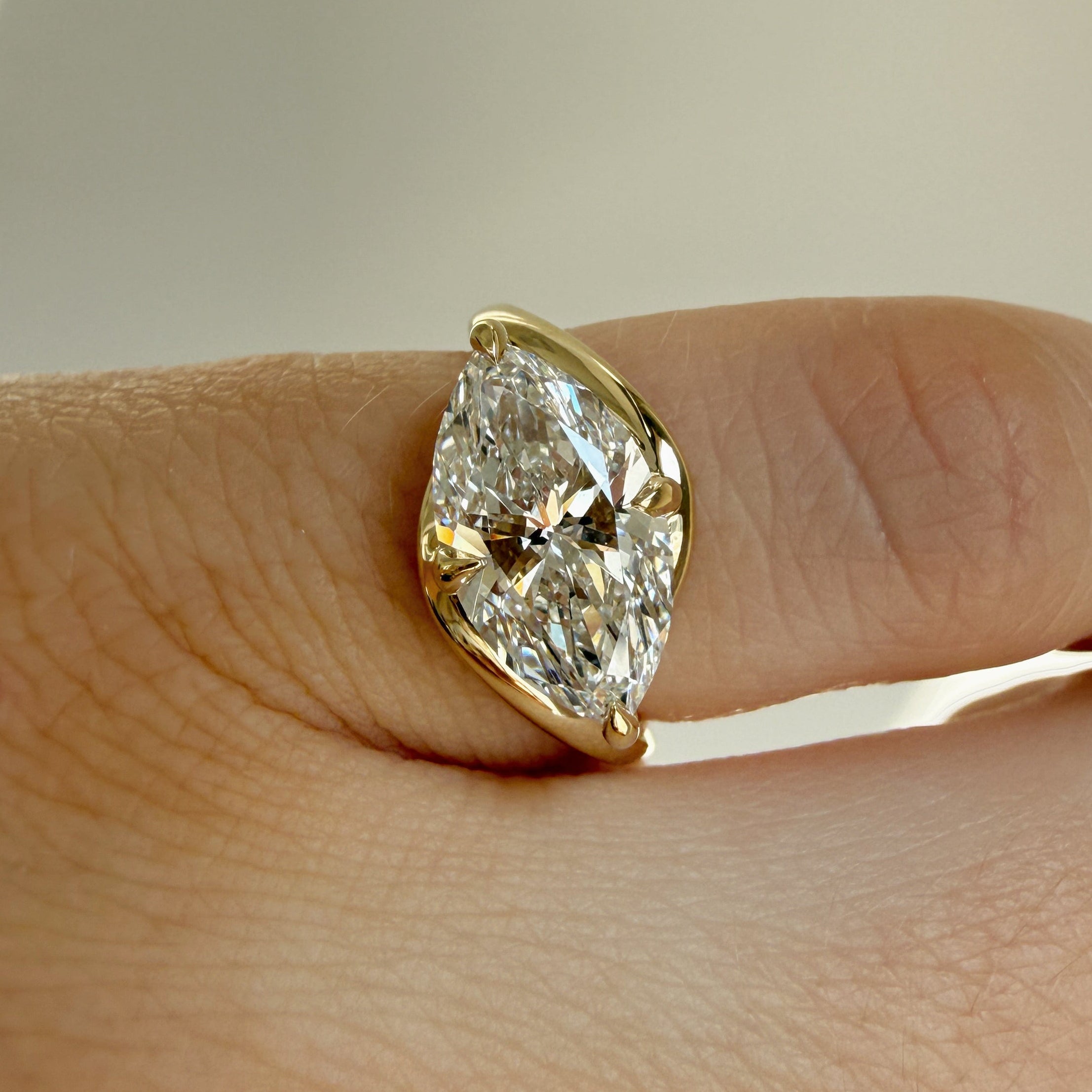 on hand shot of an east west bypass engagement ring with a marquise cut center diamond