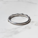The back profile of a white gold diamond wedding band sitting on a white marble backdrop.