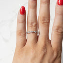 An on hand shot of a dainty white gold alternating baguette diamond wedding band. The hand has red fingernail polish.