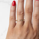 An on hand shot of a dainty alternating diamond bezel wedding band. The hand has red fingernail polish.