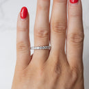 An on hand shot of a chunky diamond wedding band with a shared prong setting. The hand has red fingernail polish.