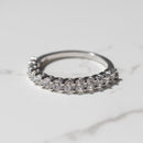 A chunky diamond wedding band with scallop prong detailing sitting on a white marble backdrop.