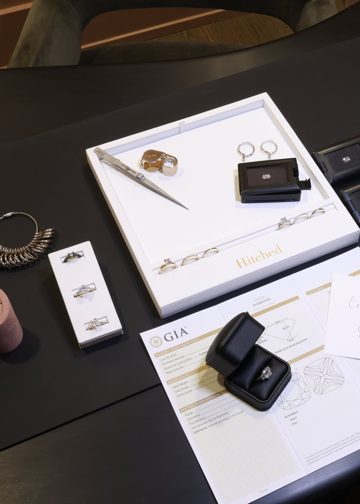 Table with jewelry and stationery items including a engagement ring box, pen, and cards.