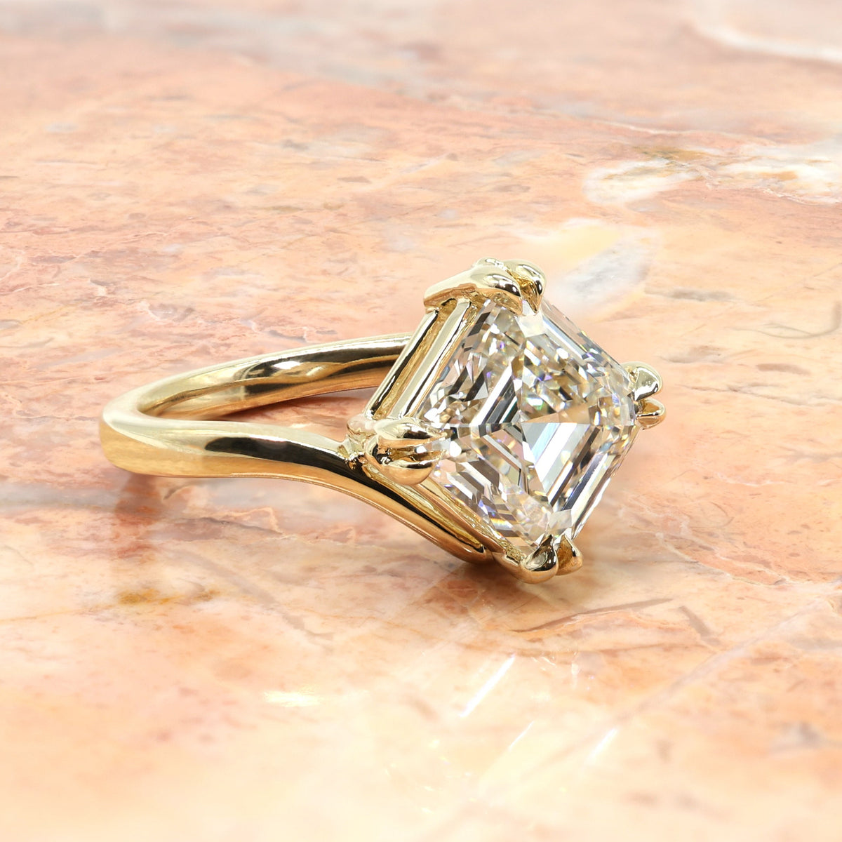 Gold ring with an asscher diamond on a marble surface