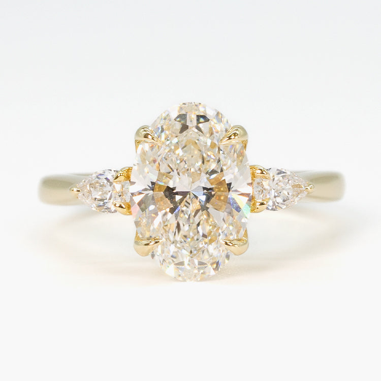 hitched yellow gold signature three-stone engagement ring with oval center and pear side stones