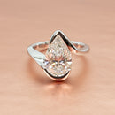 A platinum modern bypass engagement ring setting with an open, crossover shank against a rose gold backdrop