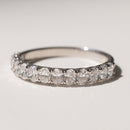 A white gold band with oval diamonds sitting on a white backdrop with soft shadows.