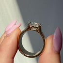 Fingers with pink nail polish holding a chunky gold engagement ring setting and showing its side profile
