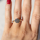 A close up, on-hand shot of a round cut diamond engagement ring. The ring has a large diamond in the center with prongs surrounding it in a yellow gold setting.