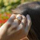 An on-hand shot of a girls hand against her hair. On her left ring finger is a large asscher cut diamond engagement ring.