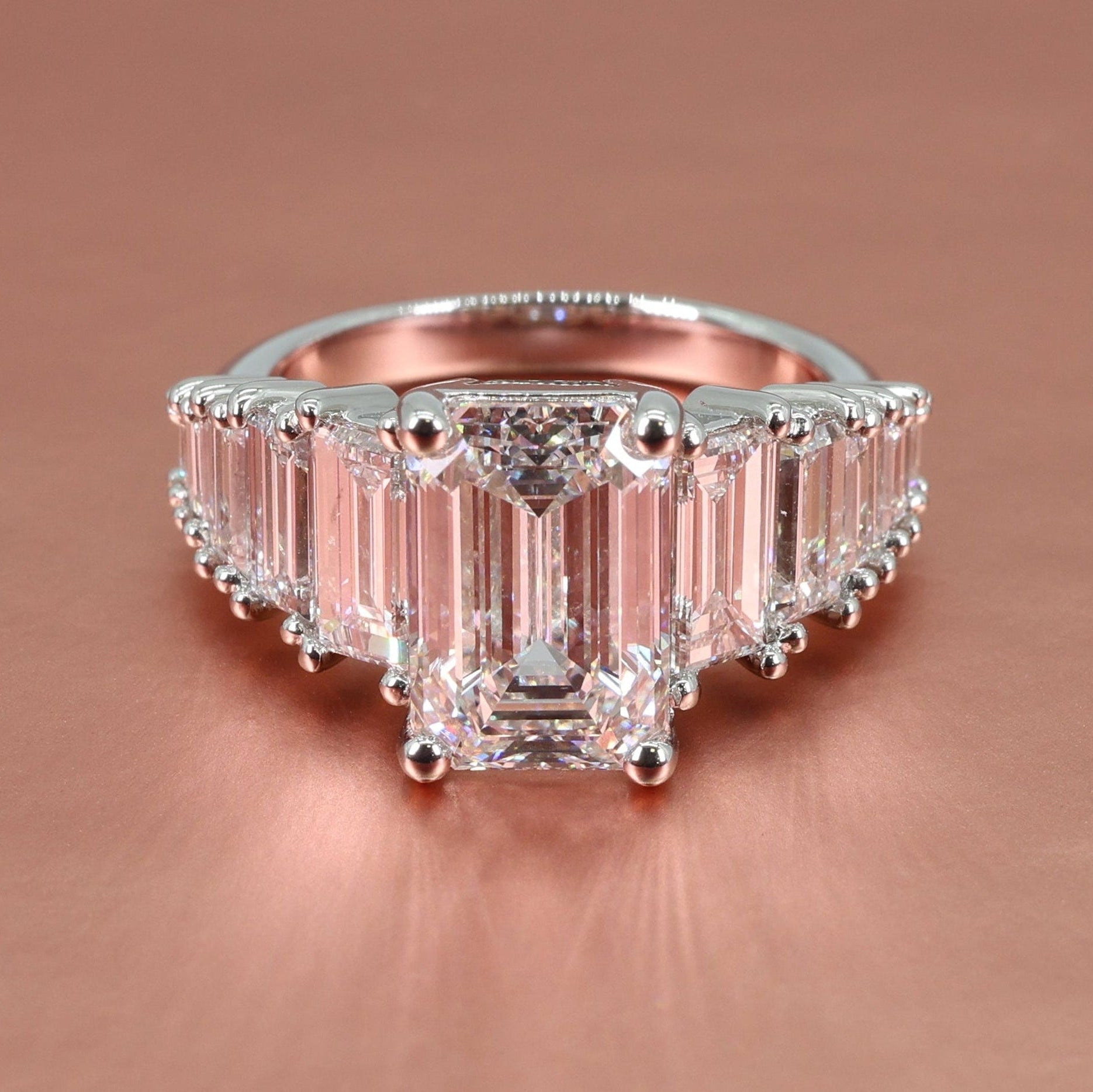 platinum tapering straight baguette engagement ring with emerald diamond center on a rose gold background