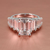 platinum tapering straight baguette engagement ring with emerald diamond center on a rose gold background