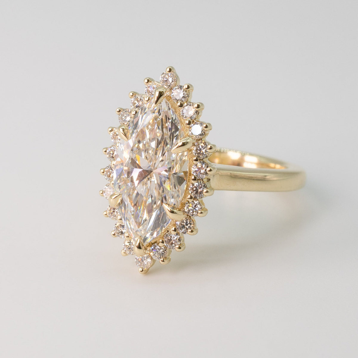 Gold ring with a large marquise diamond surrounded by a halo of smaller diamonds on a light gray background