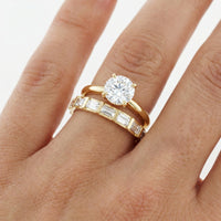 hitched women's gold diamond bar baguette wedding band with straight baguette diamonds on model with a round cut engagement ring