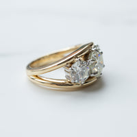 A side view of a three-stone round diamond engagement ring with a dual tone basket