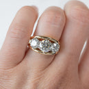 A three-stone round diamond engagement ring with a dual tone basket shown on the hand