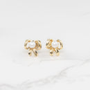 yellow gold pearl bow stud earrings on marble background lifestyle