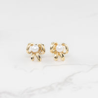 yellow gold pearl bow stud earrings on marble background lifestyle